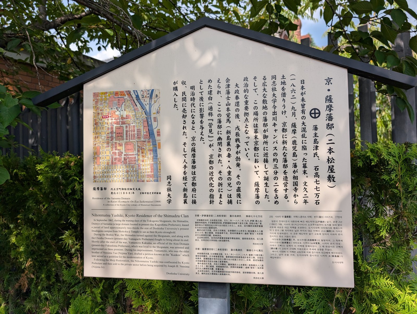 石標のそばに掲げられた説明板「京・薩摩藩邸（二本松屋敷）」。相国寺から薩摩藩、京都府、民間、新島襄へと移ったこの土地の来歴が書かれている（2026-08-22 撮影）